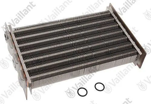 Vaillant Wärmetauscher mit mehreren Metallrippen und Anschlüssen, liegend auf einer Oberfläche, daneben zwei schwarze O-Ringe.